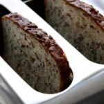 Fette biscottate integrali su un piatto con marmellata e frutta fresca per una colazione sana.